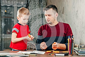 The father helps his son to do homework for the school.