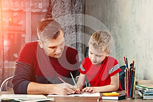 The father helps his son to do homework for the school.