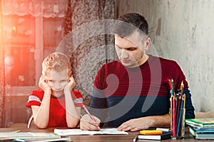 The father helps his son to do homework for the school