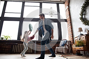 Father and his child playing together. Girl and dad having fun and fighting pillows. Family holiday and togetherness.