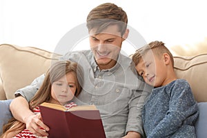 Father and his children reading book together at home