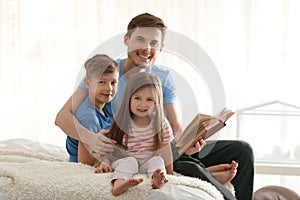 Father and his children reading book together at home