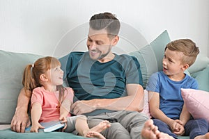 Father and his children reading book together at home