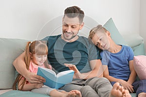 Father and his children reading book together at home