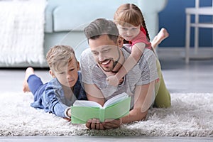 Father and his children reading book together at home