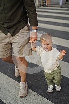 father and his cute baby son crossing road on zebra crossing holding hands