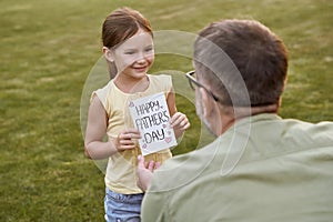 Father and his cute little daughter celebrating Happy Fathers Day in park on a warm day. Small girl giving her father