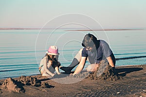 Father and his daughter build sand castles on the beach. Toned photo