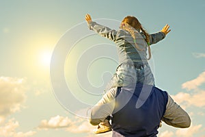 Father and his daughter playing outdoors. the child sits at the daddy on the neck,