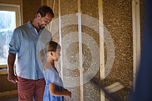 Father with his little daughter checking their unfinished wooden house, diy eco-friendly homes concept.