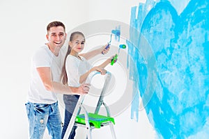 Father and his little daughter painting a wall in new home.