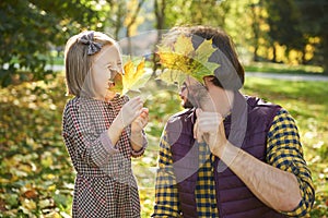 Father and his little daughter picking autumn leafs