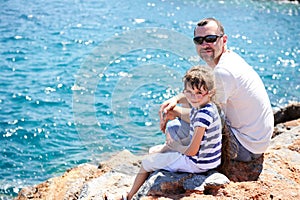 Father and his little daughter sitting on rocks