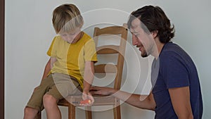 Father and his little son are assembling furniture. They assemble a kitchen chair