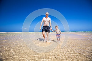 Father and his little son having fun and running on the beach.