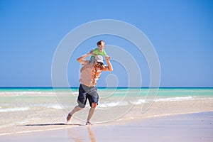 Father and his little son having fun and running on the beach.