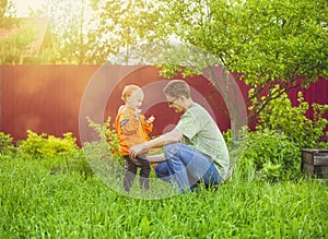 Father and his little son play in the backyard of a village house at sunset