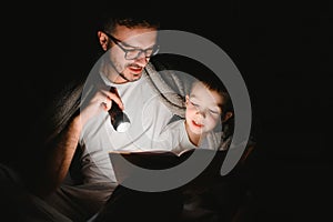 Father and his little son reading bedtime story at home.