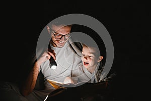 Father and his little son reading bedtime story at home.