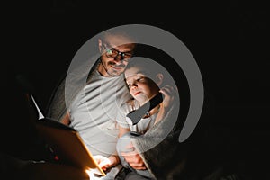 Father and his little son reading bedtime story at home.