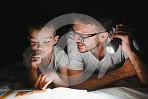 Father and his little son reading bedtime story at home.