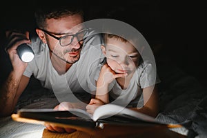 Father and his little son reading bedtime story at home.