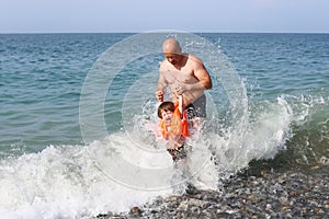 Father and his little son swimming in the wave sea