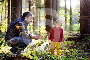 Father and his little son walking during the hiking activities in forest at sunset