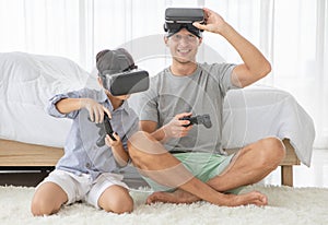 Father and his mixed-race son wearing vr virtual reality device to play a game together with fun and happy in bedroo