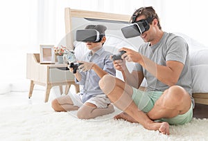 Father and his mixed-race son wearing vr virtual reality device to play a game together with fun and happy in bedroo