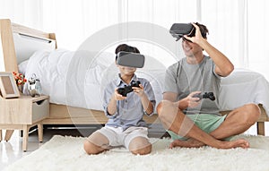 Father and his mixed-race son wearing vr virtual reality device to play a game together with fun and happy in bedroo