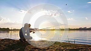 Father and his son angling on the riverside at sunset