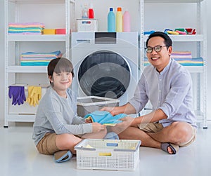 Father with his son is doing laundry in washing machine at home together for family housework togetherness concept