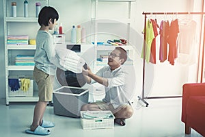 Father with his son is doing laundry in washing machine at home together for family housework togetherness concept