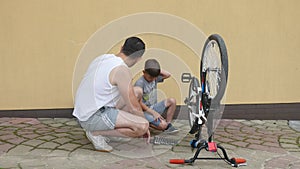 Father and his son fixing a bike on a sunny day