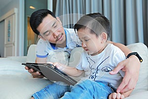 Father and his son happy having fun by gaming on a tablet.