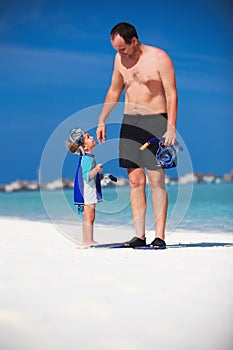 Father and his son having fun on the beach and getting ready to snorkle