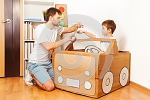 Father and his son making toy car of cardboard box
