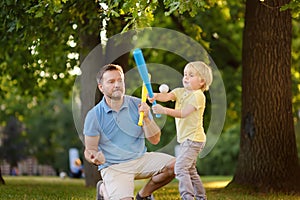 Father and his son playing baseball in park.