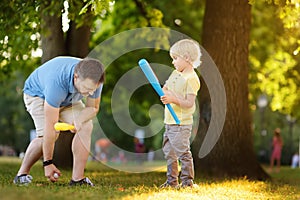 Father and his son playing baseball in park.