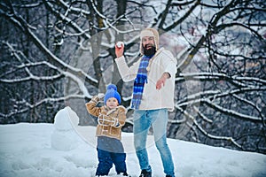 Father and his son playing outdoors. Cute little child boy and happy father on snowy field outdoor. Winter family in