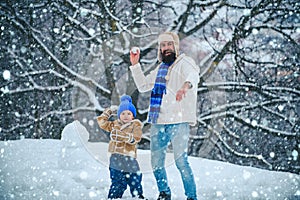 Father and his son playing outdoors. Cute little child boy and happy father on snowy field outdoor. Winter family in