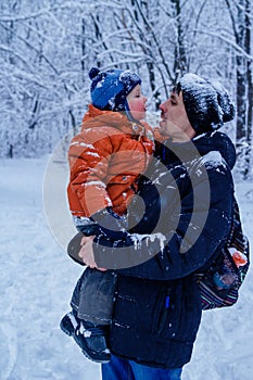 Father and his son playing outside, winter forest on the background, snowing, happy and joyful