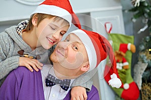 Father with his son in santa caps pose near