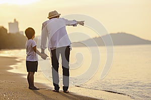Father and his son who enjoy a picnic and sea bathing at the beach on sunset in holiday.