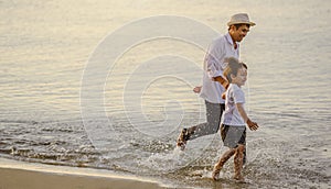 Father and his son who enjoy a picnic and sea bathing at the beach on sunset in holiday.