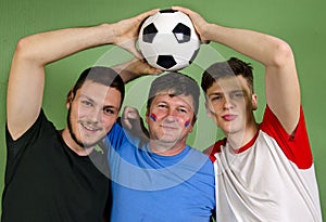 Father and his sons holding soccer ball together