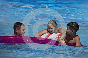 Father and his teenager son and daughter relaxing at the weekend, swimming in a pool on an inflatable pool raft