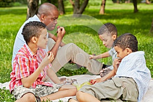 Father and his three sons sit on rag matting on