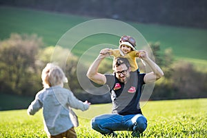 A father with his toddler children having fun outside, spring nature.